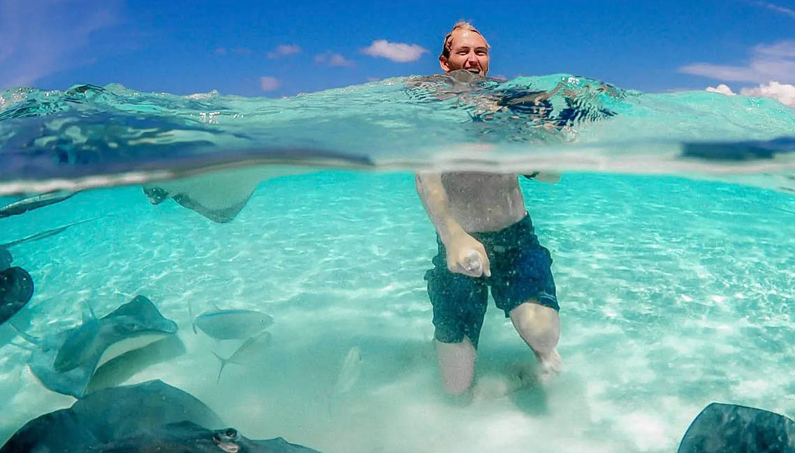 man in water with stingrays